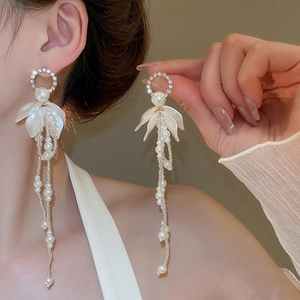 Detail of elegant pearl tassel earrings with diamond flowers and gold hardware