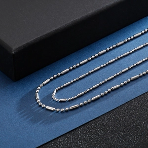 Détail d'un collier en acier inoxydable avec perles et barres sur fond bleu professionnel