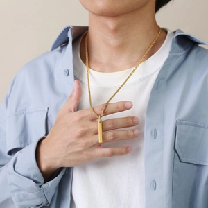 Close-up of minimalist gold bar pendant necklace worn by male model on a gold rope chain