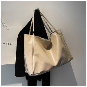 Minimalist cream beige leather tote bag hanging next to a suit jacket in a studio setting