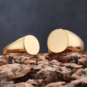 Polished gold signet rings displayed on rough tree bark with mirrored finish