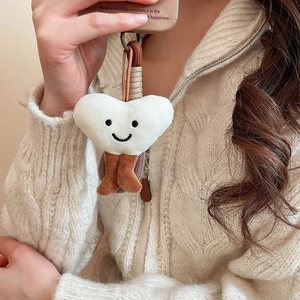 White heart plush phone charm accessory styled on a case with beige knit background