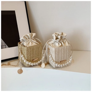 Detailed view of woven straw handbags with pearl handles and gold chain straps