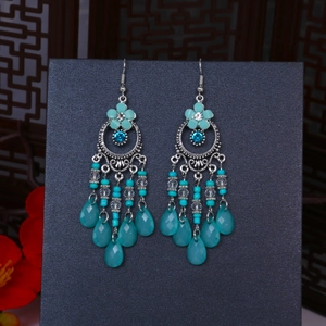 Dettaglio macro di orecchini boho con frange, perline a goccia verde acqua e argento