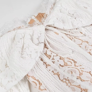 Close-up of white lace fabric detailing with floral mesh pattern and pink lining trim