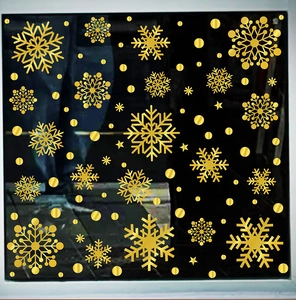 Detail of golden snowflake window stickers and gold star decals on a dark glass surface