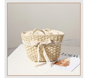 Detailed close-up of beige straw basket bag featuring white lace trim and bow accent