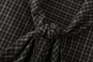 Detailed view of the dark plaid shirt fabric with a stylish knot and cotton texture