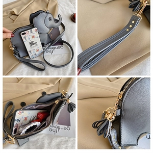 Detail view of grey elephant crossbody bag featuring gold hardware and tassel zippers
