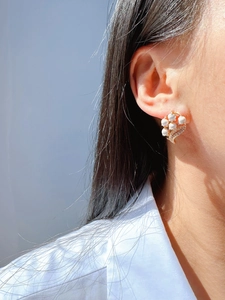 Close-up of elegant lily of the valley earrings with white enamel and golden leaves