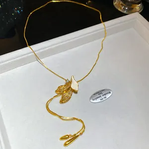 Macro detail of French gold petal pendant with white enamel inlay and tassel chains