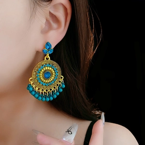 Detailed view of vintage gold flower earrings with blue rhinestones on a model