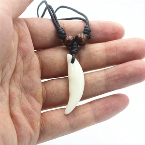 Close-up of faux wolf tooth pendant with brown wooden beads on black cord necklace