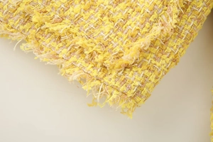 Close-up of yellow tweed fabric showing intricate weave and fringe edge detail