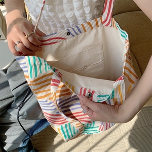 Detail view of corduroy tote showing striped texture, magnetic buckle, and inner pocket