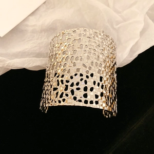 Close-up of silver hollow woven metal armlet with intricate artistic mesh structure