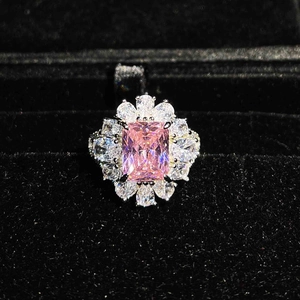 Detailed close-up of a square pink gemstone ring with white accents in a velvet box