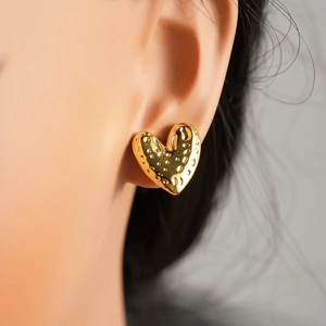 Detail of gold heart earrings featuring unique dotted texture on the metal surface