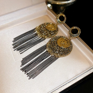 Makroaufnahme der Retro-Münzohrringe mit schwarzen Metallfransen-Quasten in Schmuckschatulle