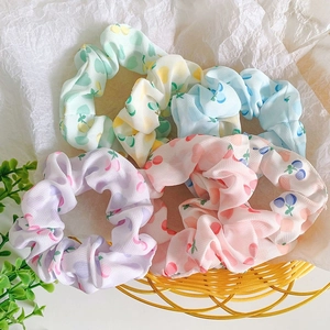 Detail of four colorful cherry pattern scrunchies in a yellow basket for hair styling