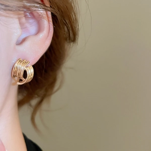 Close-up of golden geometric layered curve earrings worn by a model in warm lighting