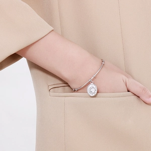 Bracelet jonc en acier argenté avec pendentif soleil sur une manche de blazer