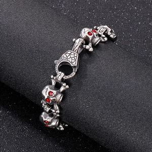 Macro shot of silver hip hop skull bracelet featuring red rhinestone eyes and lobster clasp