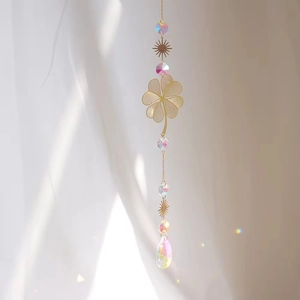 Macro shot of golden four-leaf clover suncatcher with colorful crystal prisms hanging