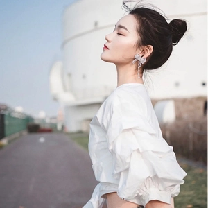Elegant silver bow earrings with sparkling tassels worn by a model in outdoor lighting