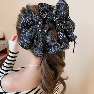 Detail view of large black paisley bow hair claw clip with pearls on model back profile
