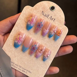 Macro detail of 3D almond press-on nails with floral patterns and pearl accents