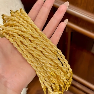 Detail of gold twisted rope bracelet with sparkling frosted finish held in hand