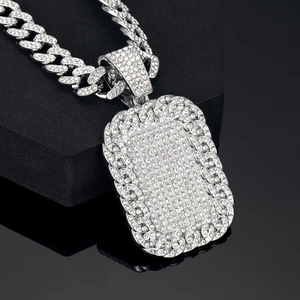 Close-up of silver Cuban link necklace with rectangular rhinestone pendant on black background