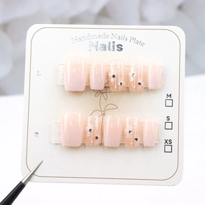 Macro view of handmade pink gradient press-on nails with white flowers and small crystals
