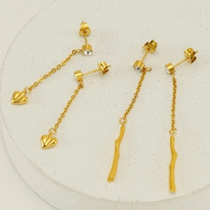 Detail of gold-plated tassel earrings with heart and branch charms and cubic zirconia