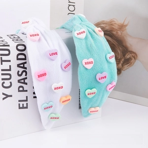 Detail of soft coral fleece headbands with colorful heart patches and XOXO embroidery