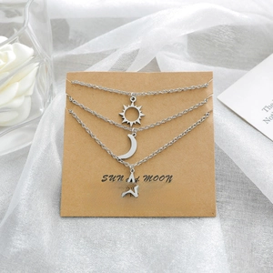 Détail de l'ensemble de colliers soleil, lune et étoile sur carte cadeau sur tissu blanc