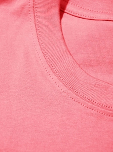 Detailed macro view of reinforced crew neck stitching on a pink cotton T-shirt