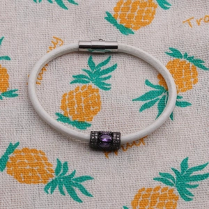Fashion leather bracelet with purple zircon beads and magnetic clasp on tropical background