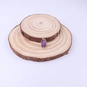 Macro detail of handmade wire-wrapped amethyst pendant on decorative wooden discs