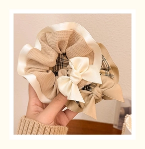 Close-up of elegant cream waffle fabric and plaid bow scrunchies with satin ribbon detail