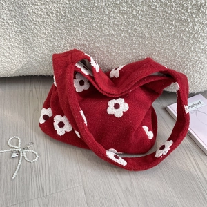 Dettaglio borsa tote in peluche rossa con motivi floreali e ciondolo con fiocco