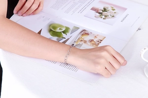 Close-up of interlocking silver oval link bracelet worn on a female wrist in a lifestyle set