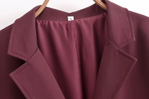 Gros plan du revers et de l'étiquette de taille S sur ce trench-coat bordeaux élégant