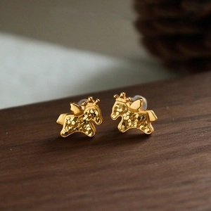 Gros plan de boucles d'oreilles cheval ailé plaquées or 24k sur une surface en bois