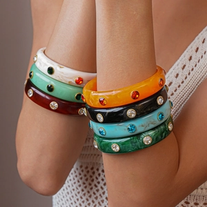 Close-up of colorful geometric acrylic bangles with rhinestones worn by a model