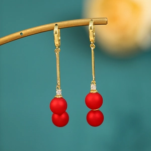 Detail of drop earrings with long gold chain, red frosted beads, and crystal accents