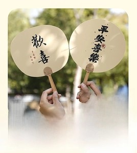 Detail of PP plastic hand fans with traditional Chinese calligraphy in a park setting