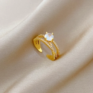 Detail of twisted gold-plated open ring with white zircon on silk background