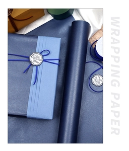 Macro shot of matte blue gift wrapping paper with silk ribbon and silver wax seal stamp